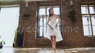 穿着白色芭蕾舞裙和芭蕾舞鞋的年轻芭蕾舞演员正在练习舞蹈动作。 穿着芭蕾舞裙跳舞的年轻舞女